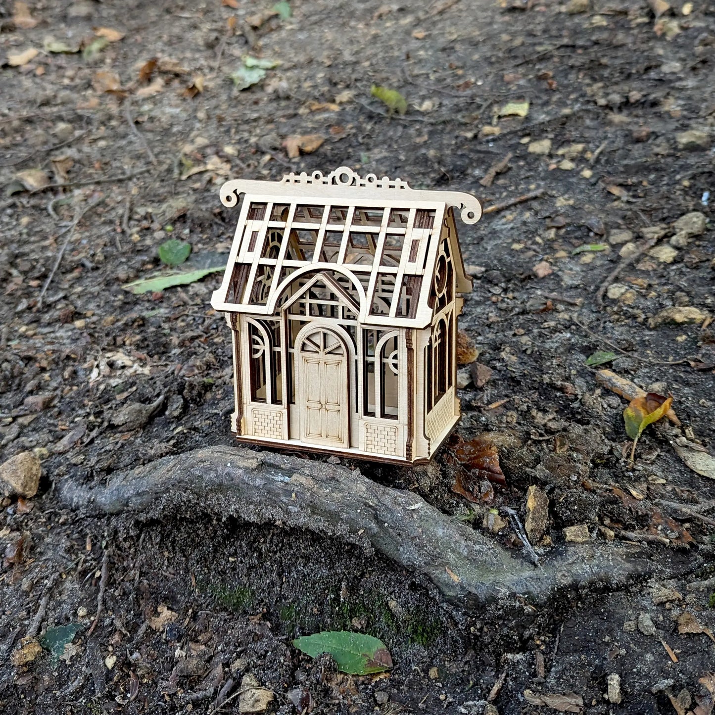 Stunning wide spring holiday lifestyle staging shot of a decorative 3D mini greenhouse model made from laser cut plywood.