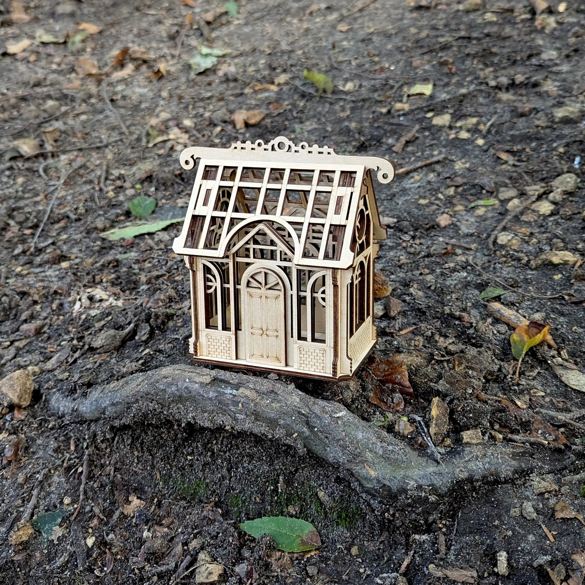 Stunning wide spring holiday lifestyle staging shot of a decorative 3D mini greenhouse model made from laser cut plywood.
