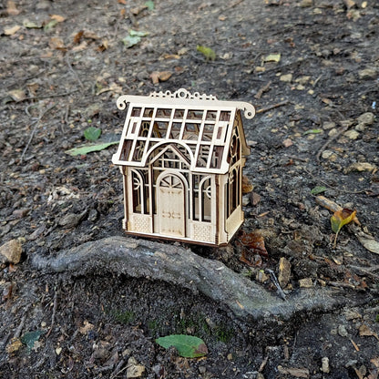 Stunning wide spring holiday lifestyle staging shot of a decorative 3D mini greenhouse model made from laser cut plywood.