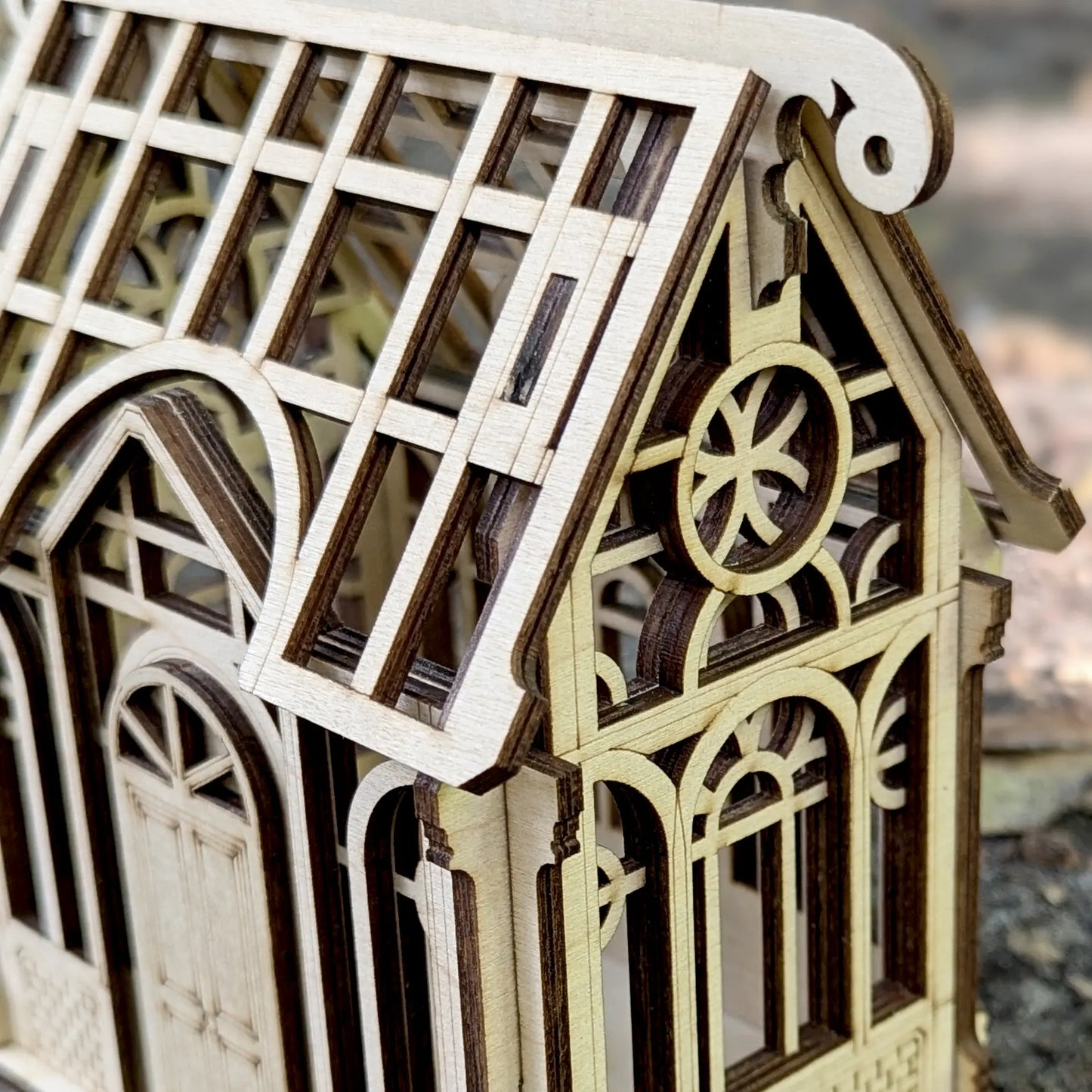 Three-quarter product shot of an intricate 3D miniature greenhouse terrarium puzzle crafted from fine laser cut plywood.