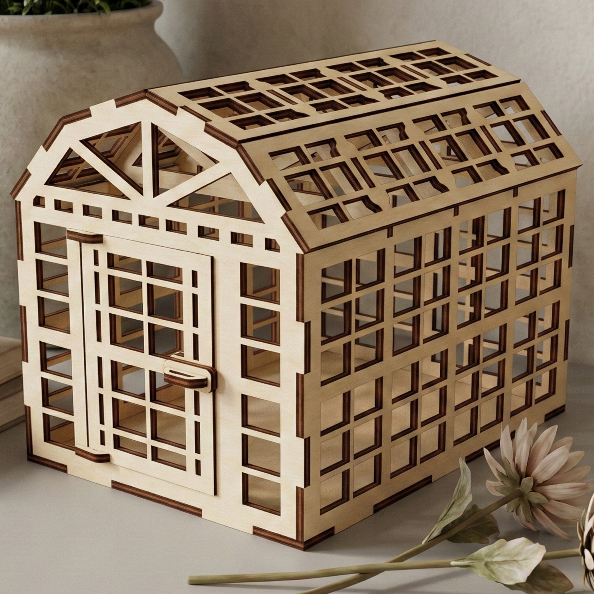 Elegant laser cut wooden greenhouse with classic barn-style roof, open sides, and precise beam details, presented against a warm neutral indoor background.