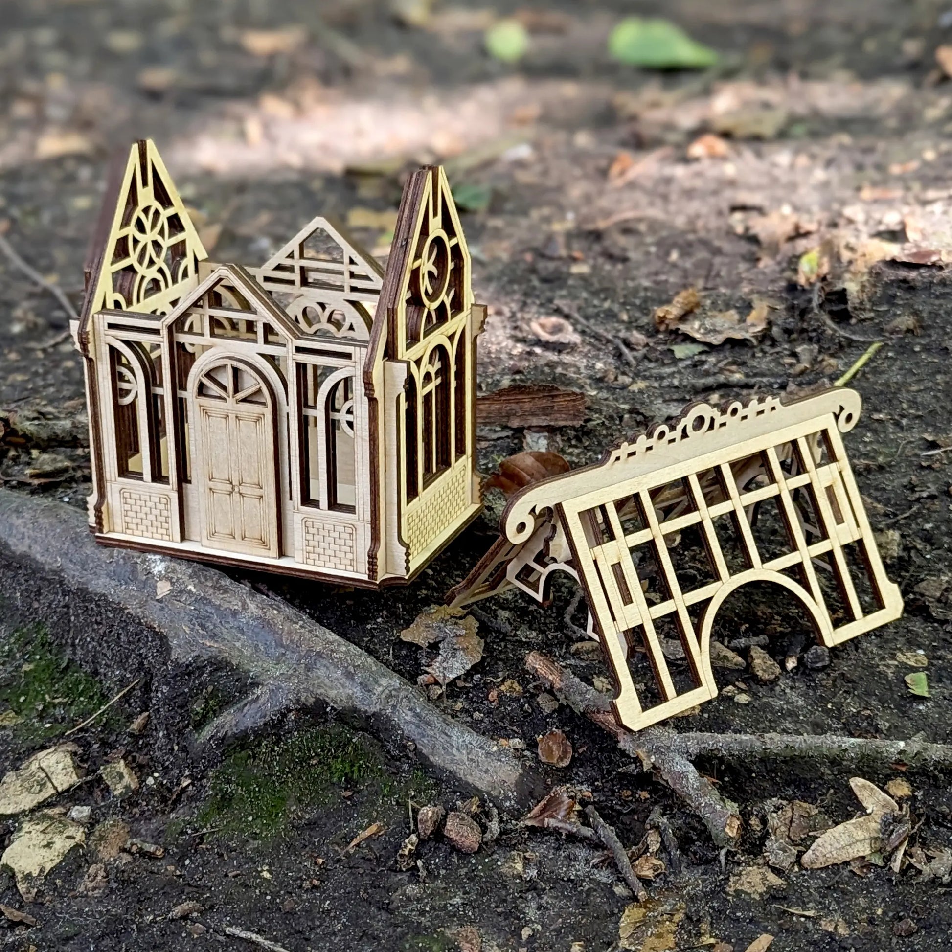 A stunning wide spring lifestyle staging shot of a decorative 3D greenhouse model base made of detailed laser cut plywood.