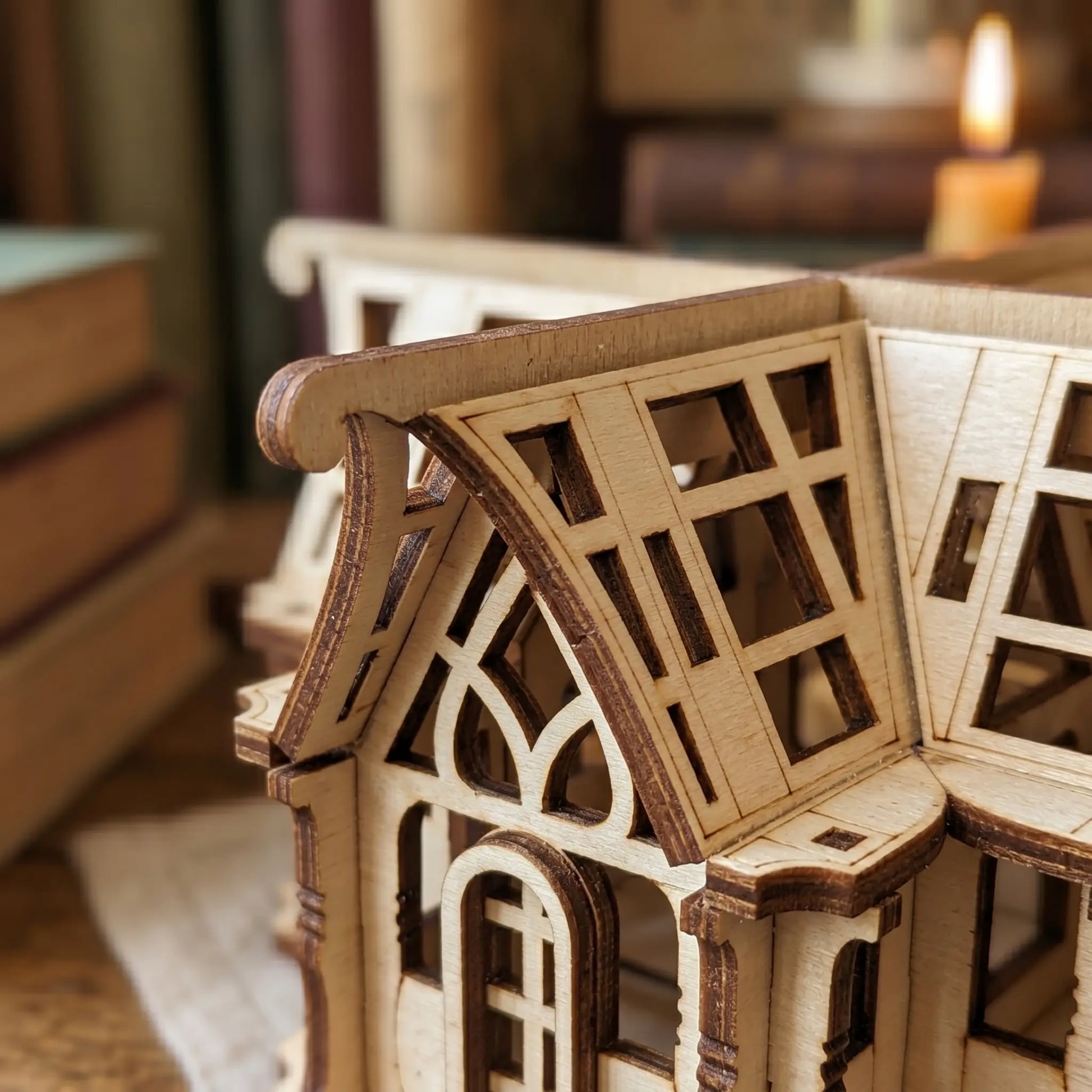 Close-up of a wooden model house with intricate detailing in a blurred indoor setting.