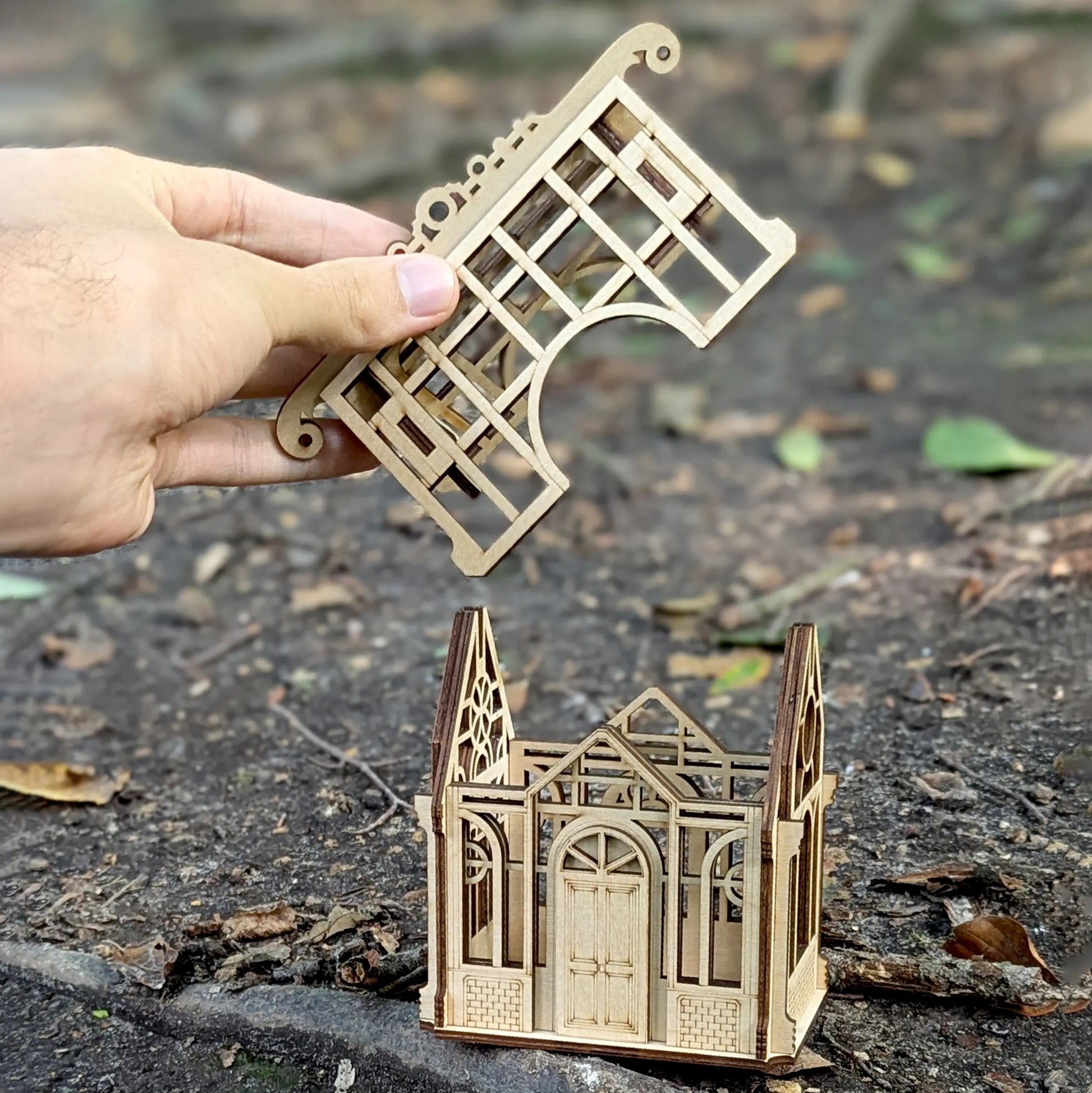 Staged lifestyle photography of an illuminated 3D miniature greenhouse centerpiece crafted out of premium laser cut plywood.