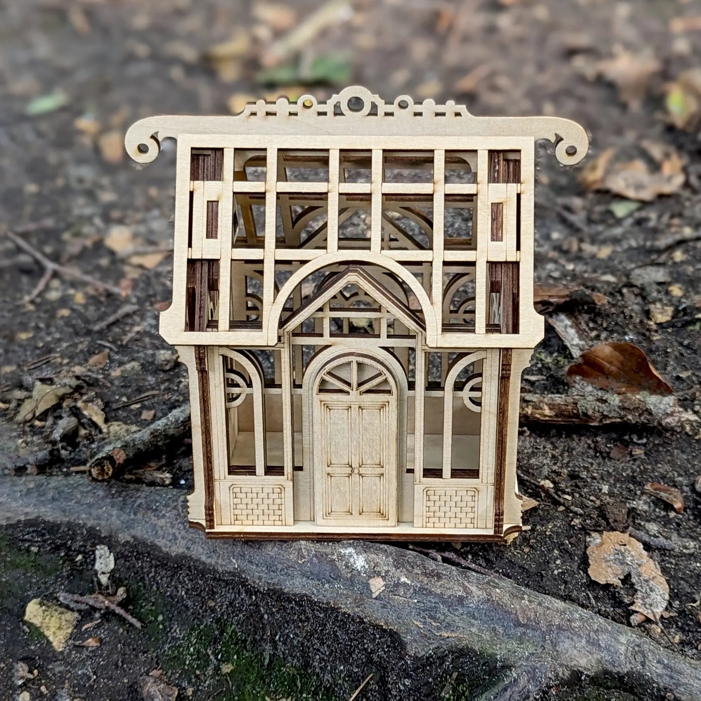 High-angle view focusing on the internal plant shelves of a miniature greenhouse model made from detailed laser cut plywood.