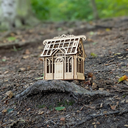 A lovely high-angle holiday staging product shot of an assembled miniature greenhouse house puzzle made of laser cut plywood.