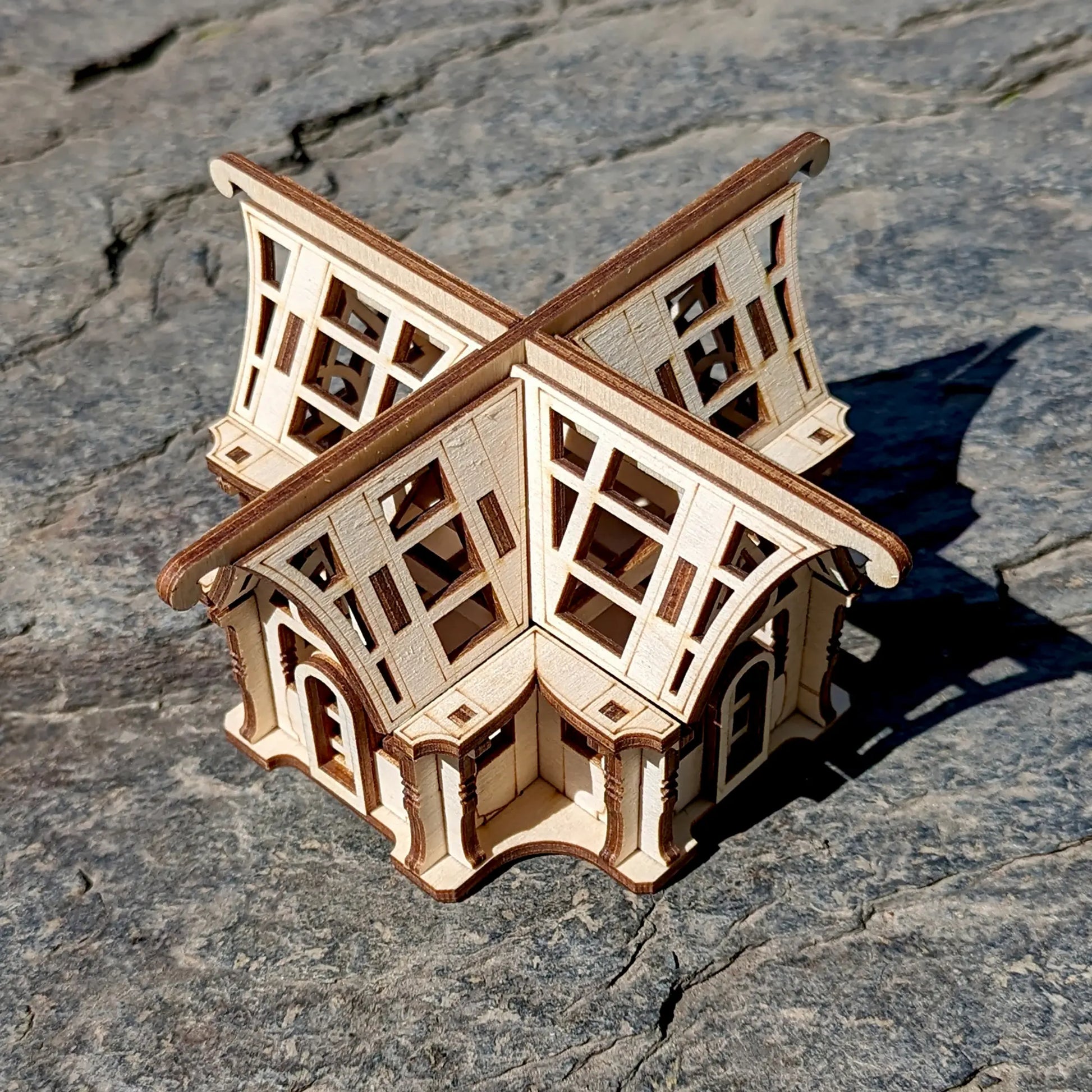 Top-down look of a cross-shaped mini greenhouse conservatory craft project assembled from laser cut plywood panels.