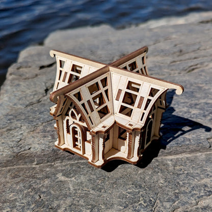 Back side perspective view of a mini traditional glasshouse cottage prototype constructed out of laser cut plywood rows.