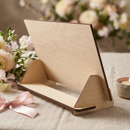 Rear view of a laser-cut plywood greeting card showing the simple wooden display stand. Highlights the natural light wood grain and clean, dark laser-cut edges. Posed in a romantic setting on a linen tablecloth with a pink ribbon and flowers.