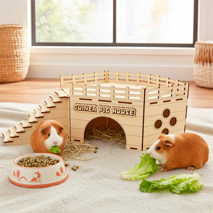 Laser cut wooden plywood Guinea Pig House with an arched entrance and side windows, featuring stairs leading to a fenced rooftop platform. The light wood structure is displayed on a fluffy white rug with hay, a food bowl, and two live guinea pigs eating lettuce, clearly showing the scale and function as a pet hideaway 