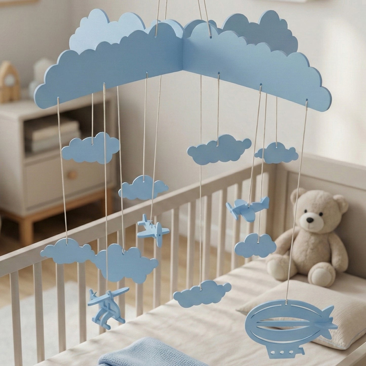 Pale blue laser cut wooden hanging toy featuring clouds, airplanes, and a dirigible, designed as a nursery crib mobile.