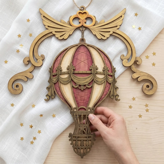A hand holds a decorative wooden hot air balloon ornament laser cut model