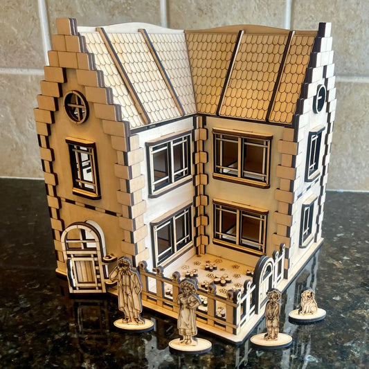 Laser cut plywood dollhouse on a dark counter, with wooden family figures placed around a small fenced yard with flowers