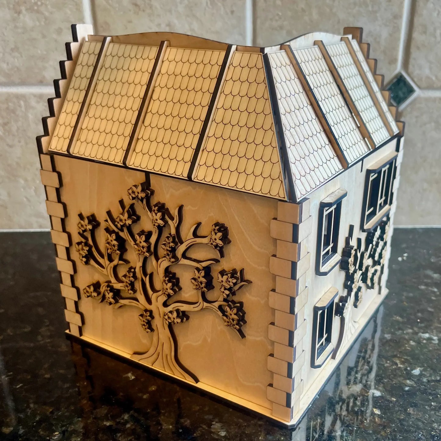 Back view of a laser cut plywood dollhouse featuring a large engraved blooming tree across the entire natural wood wall.