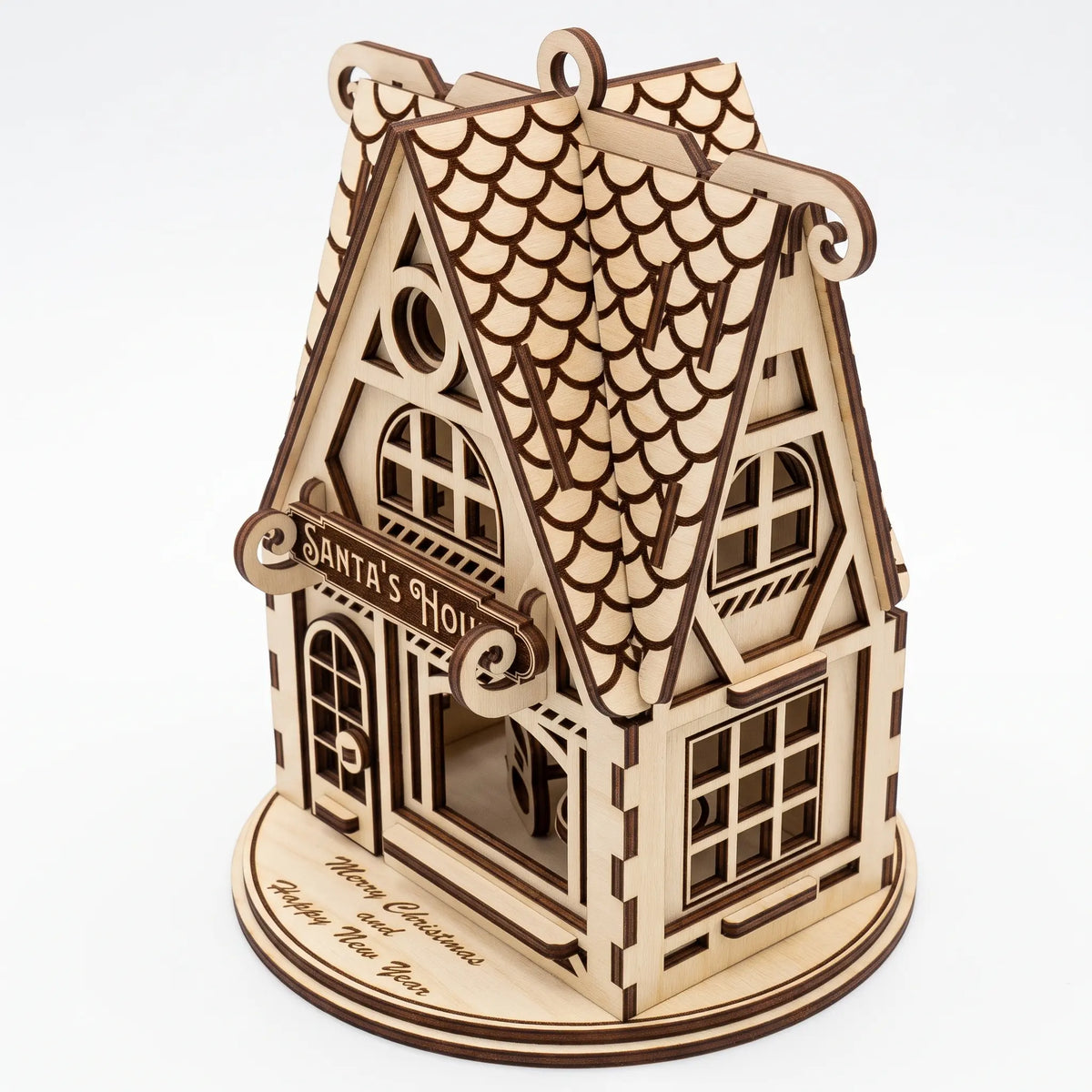 High-angle view of laser cut plywood Santa's House ornament showing curved shingle roof on white base.