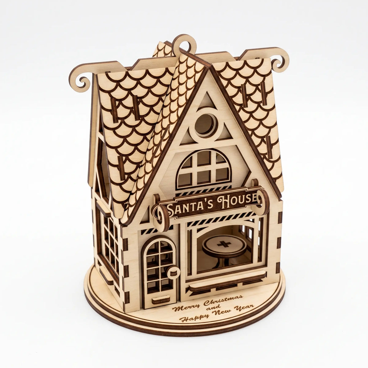 Side perspective of laser cut plywood Santa house model with engraved roof and stand on white backdrop.
