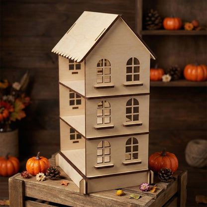 Front view of a 3-story miniature house display stand in natural laser cut plywood. Showcases detailed window frames and smooth wood texture. Set against a dark wooden background with seasonal fall decor like pumpkins and dried flowers.