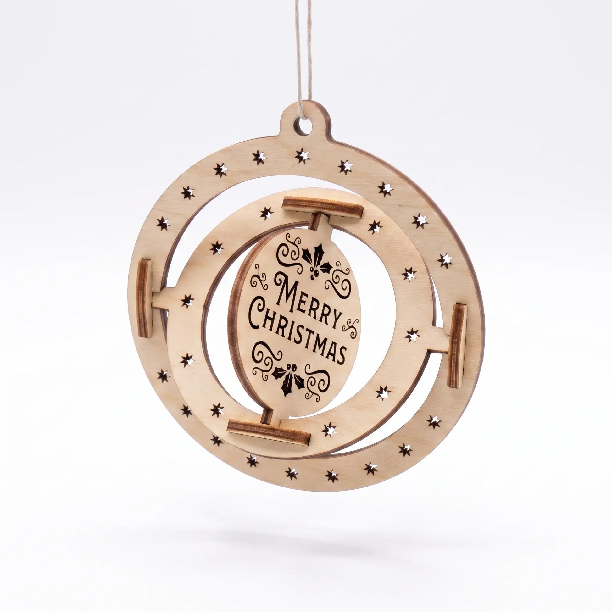 Angled hanging laser cut plywood kinetic bauble showing rotated Merry Christmas center disc against plain white