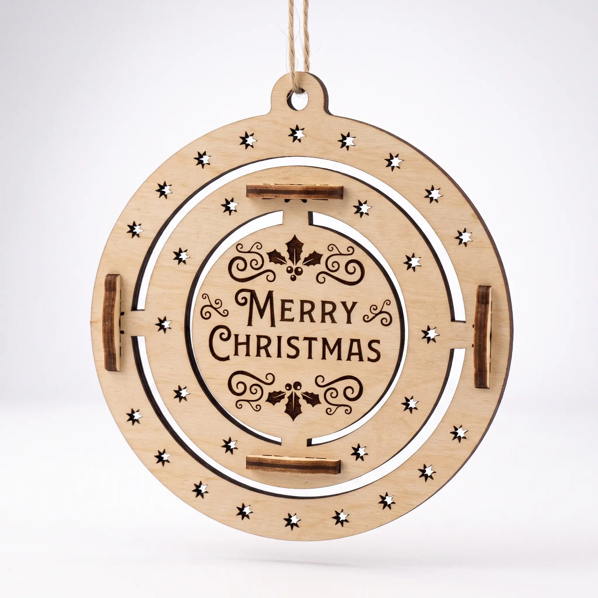 Front view of flat laser cut plywood Merry Christmas bauble with star cutouts suspended isolated on white backdrop