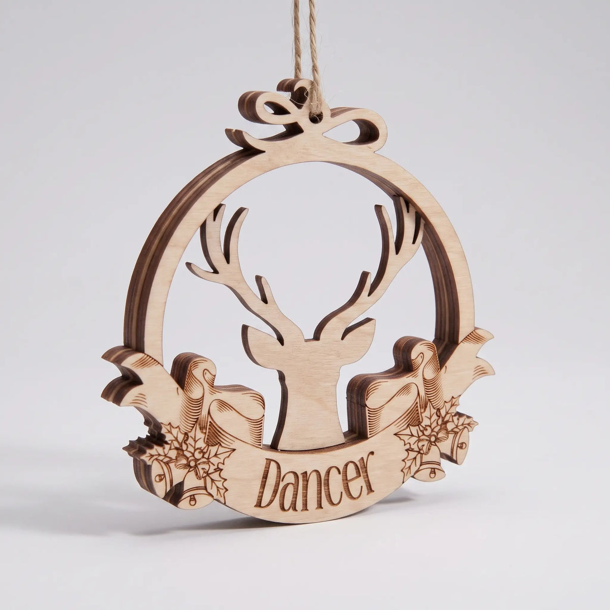 Perspective view of layered laser cut plywood Dancer reindeer bauble with bow hanger standing on white surface.