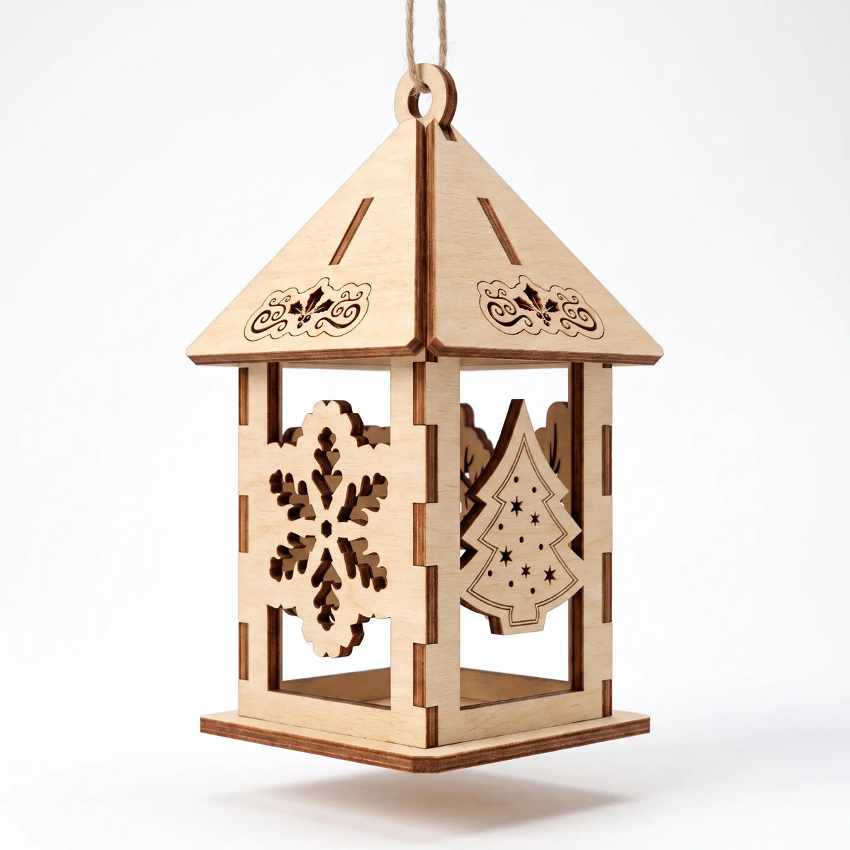 Laser cut plywood holiday lantern ornament featuring snowflake and Christmas tree panels, isolated on plain white