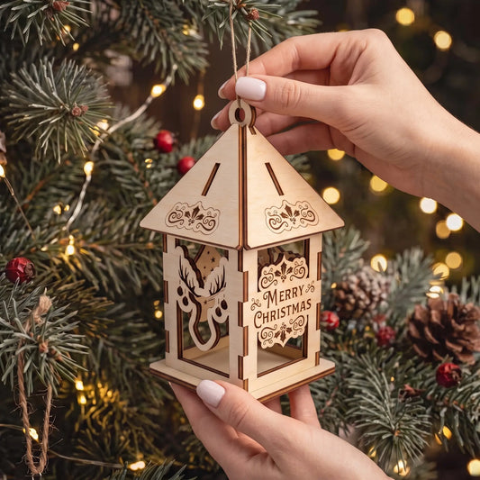 Hands hold hanging laser cut plywood holiday lantern ornament showing scale in front of warm Christmas tree lights.