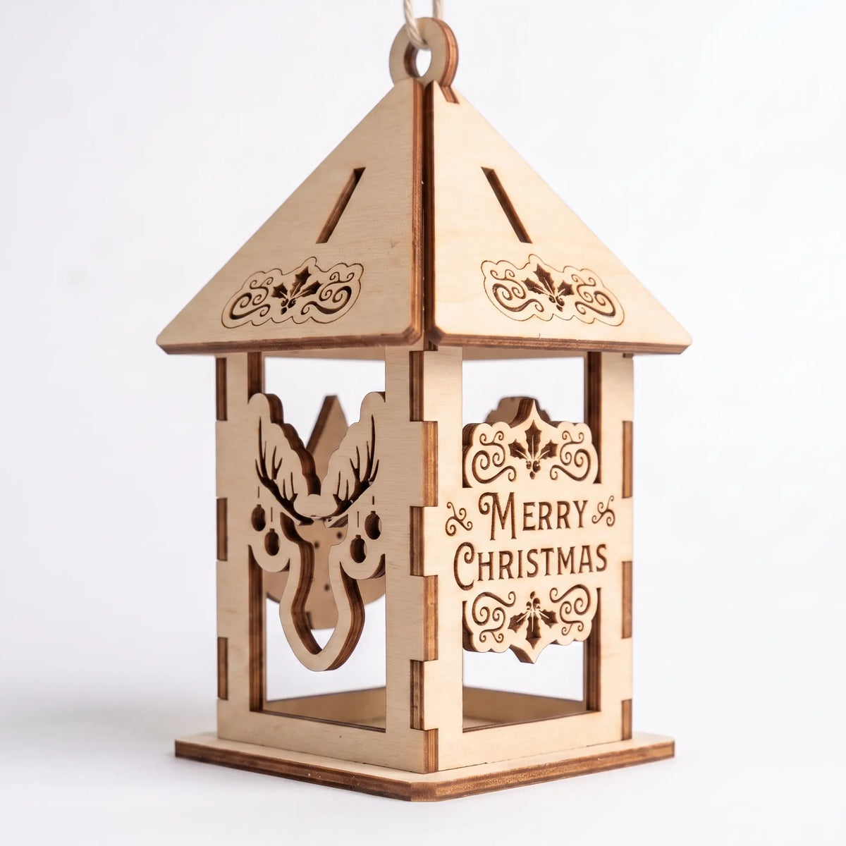 Assembled laser cut plywood holiday lantern with deer silhouette and Merry Christmas panel standing on white base