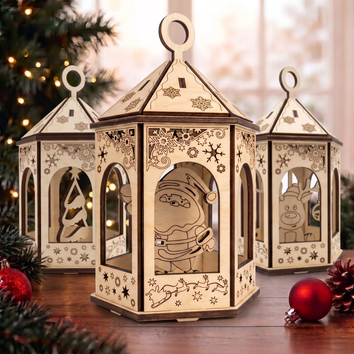 Set of three laser cut plywood Christmas lantern ornaments with festive silhouettes and red baubles on table