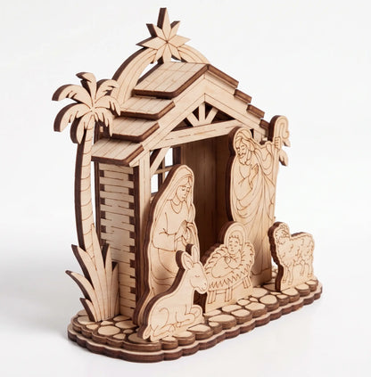 Side perspective view of assembled laser cut plywood nativity creche with stable and figurines on white backdrop.