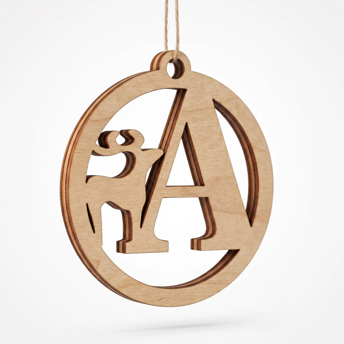 Angled close-up of hanging laser cut plywood letter A bauble with deer cutout, showing layered cut edge on white.