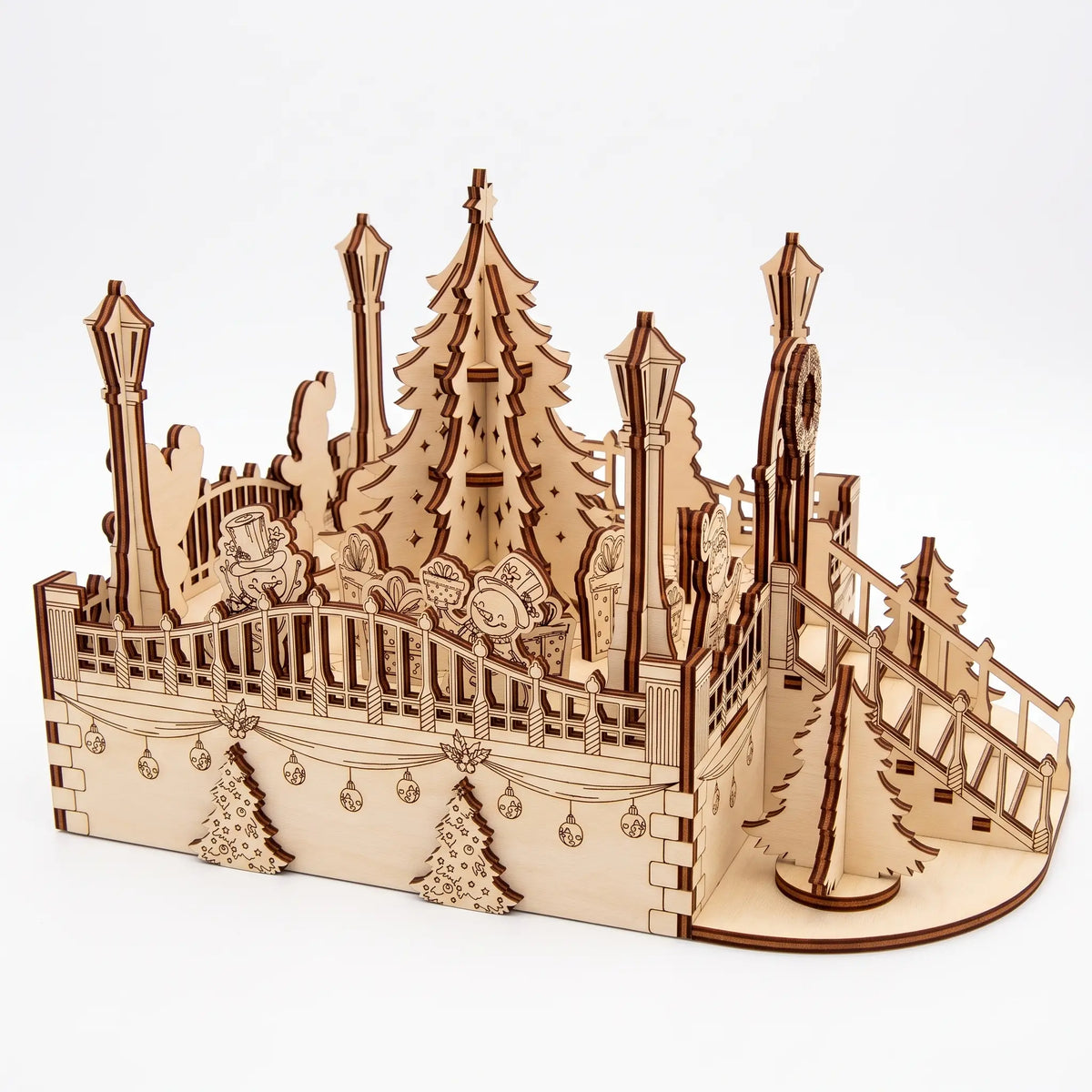 Side-angle view of laser cut plywood holiday plaza diorama showing side balustrade, snowmen, and corner staircase.