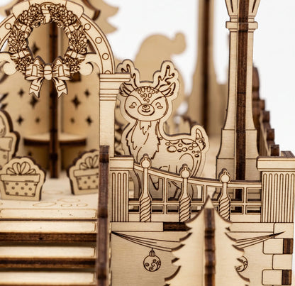 Macro view of laser cut plywood holiday town square diorama highlighting engraved deer figure, wreath, and railings