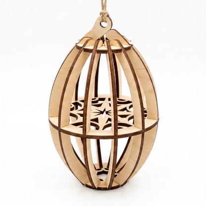 Assembled 3D oval laser cut plywood Christmas bauble ornament with internal snowflake disc, on white background.