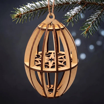 3D geometric laser cut plywood oval bauble ornament hanging from snow-dusted pine branches on a dark backdrop.