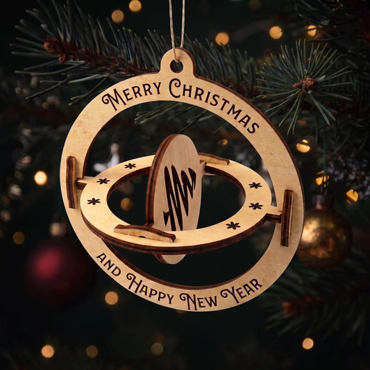 Kinetic laser cut plywood 3D sphere ornament with spinning pine tree center hanging on a lit Christmas tree.
