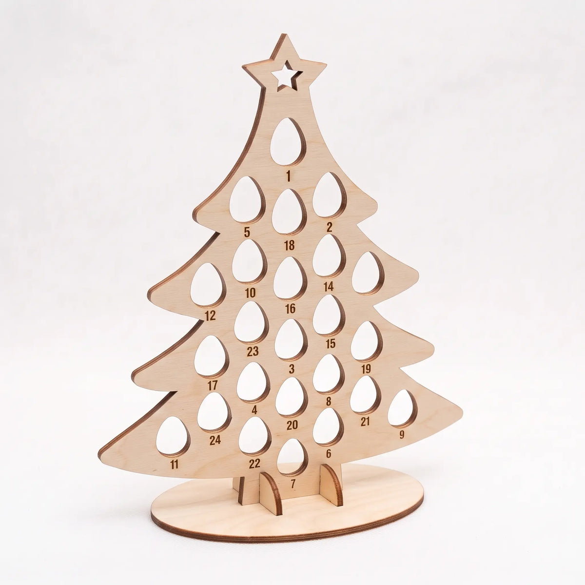 Angled view of empty laser cut plywood Christmas tree advent calendar stand with egg cutouts on white backdrop