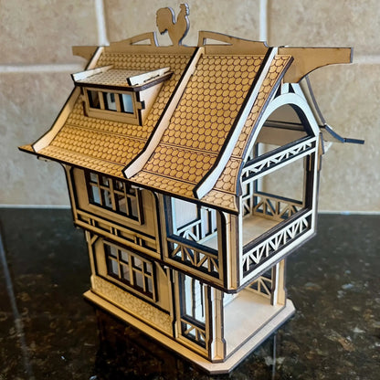 Side angle view of a medieval laser cut plywood house showing open balconies, interior floors, and a rooster weather vane.