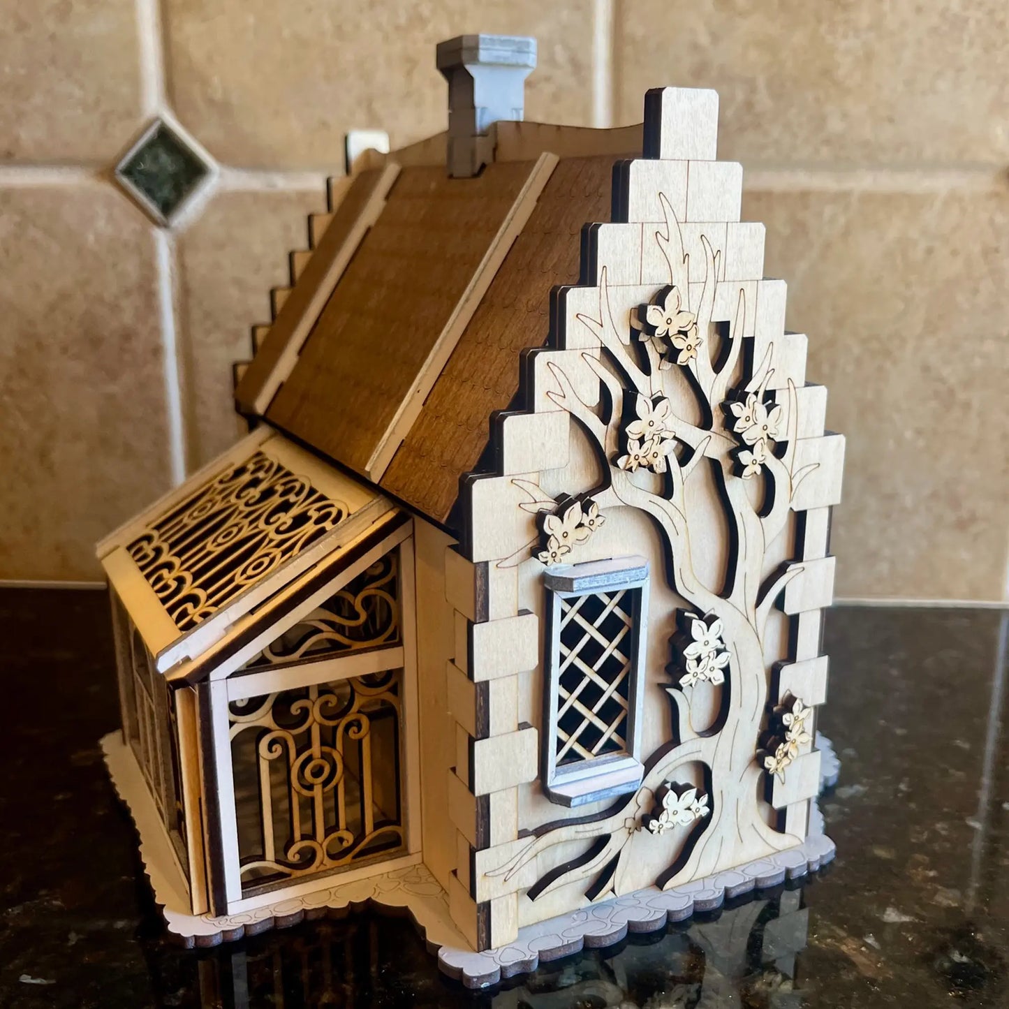 Side view close-up of a decorative miniature conservatory greenhouse attached to a dollhouse made from laser cut plywood.