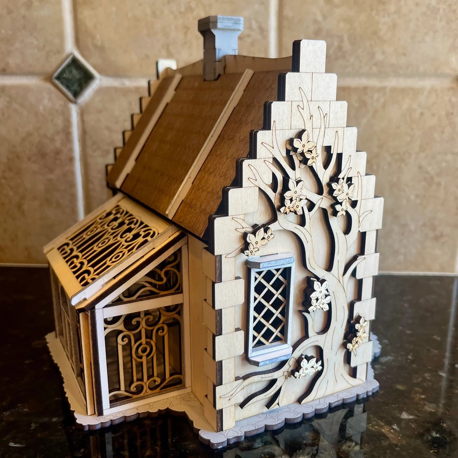 Side view close-up of a decorative miniature conservatory greenhouse attached to a dollhouse made from laser cut plywood.