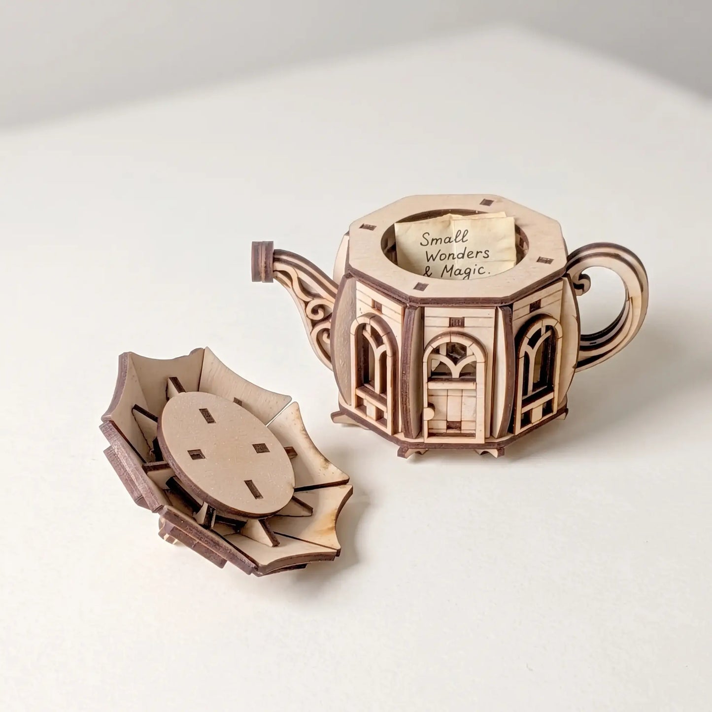 Wooden tea pot model with 'Small Wonders & Magic' text on a white background
