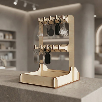Professional laser cut plywood display rack for keychains on a concrete counter in a modern boutique. The stand holds various metallic and black keychains on its hooks, with a sturdy interlocking wood design ideal for high-end retail environments.