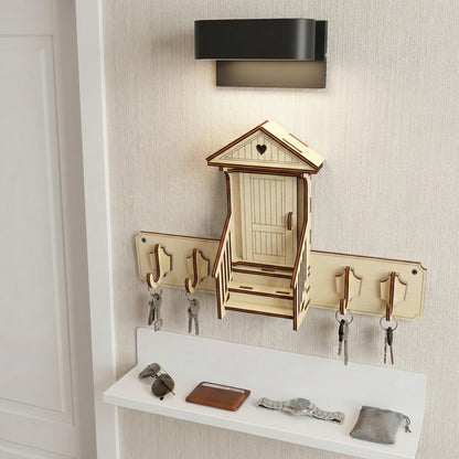 Laser cut wooden keyholder designed as a cozy house entrance with heart window, multiple key hooks, and integrated shelf, in a softly lit hallway background.