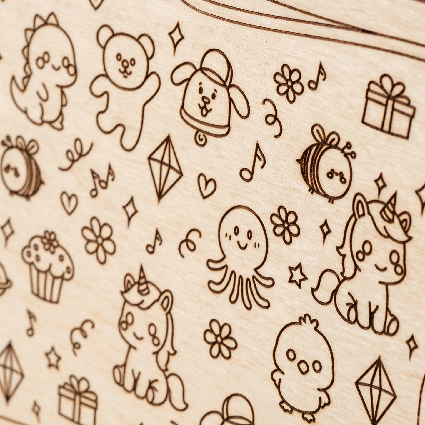 Close-up of a laser cut plywood surface featuring engraved cute characters like unicorns, bears, and bees.