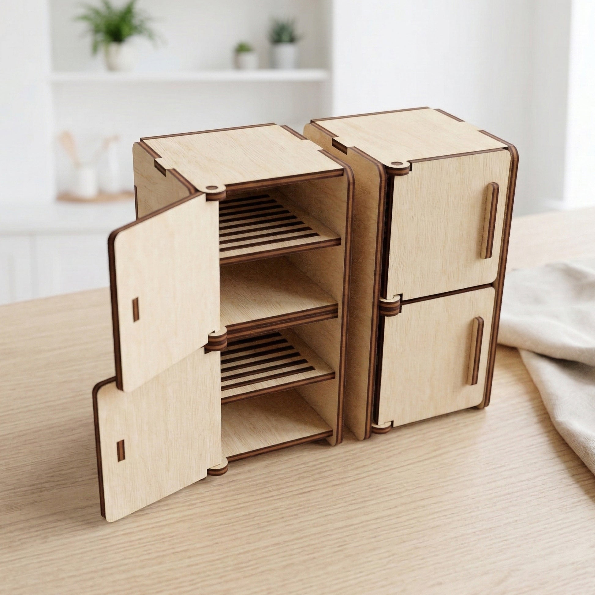Pair of miniature dollhouse refrigerator units made of laser cut plywood. One unit is open, showing multiple interior shelves with slatted details. The doors have vertical handles and visible hinges, showcasing a natural wood finish.
