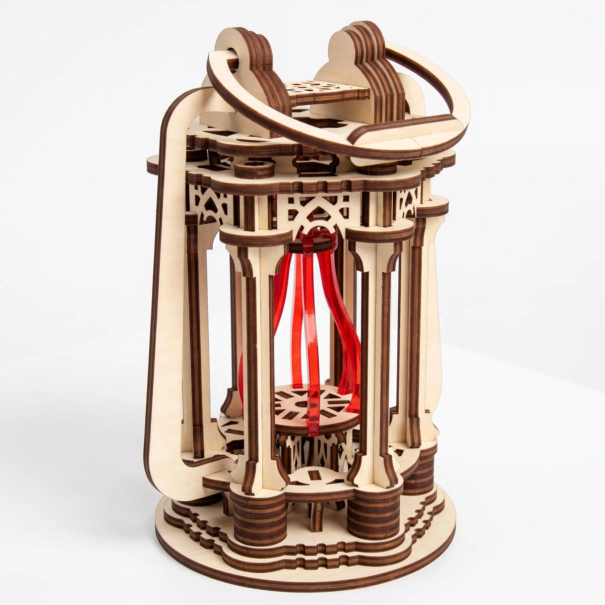 High angle view of intricate 3D laser cut plywood lantern model with top swing handle and red core on white backdrop.