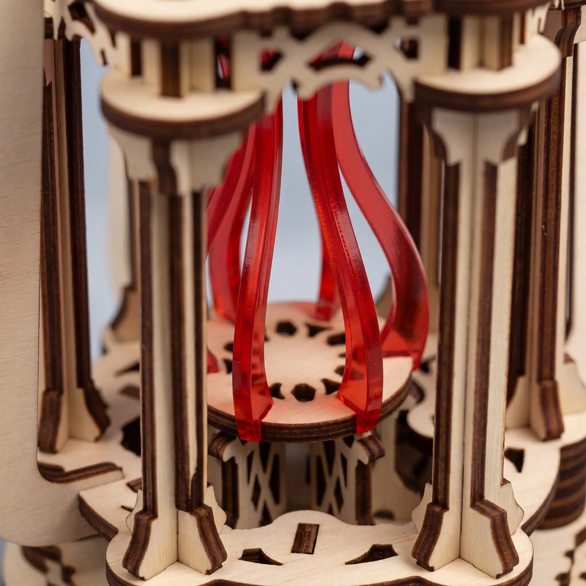Close-up of laser cut plywood lantern interior showcasing slotted architectural pillars and red acrylic flame center.