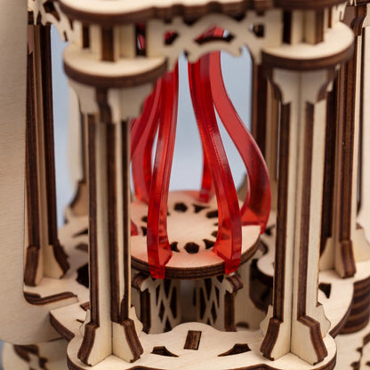 Close-up of laser cut plywood lantern interior showcasing slotted architectural pillars and red acrylic flame center.