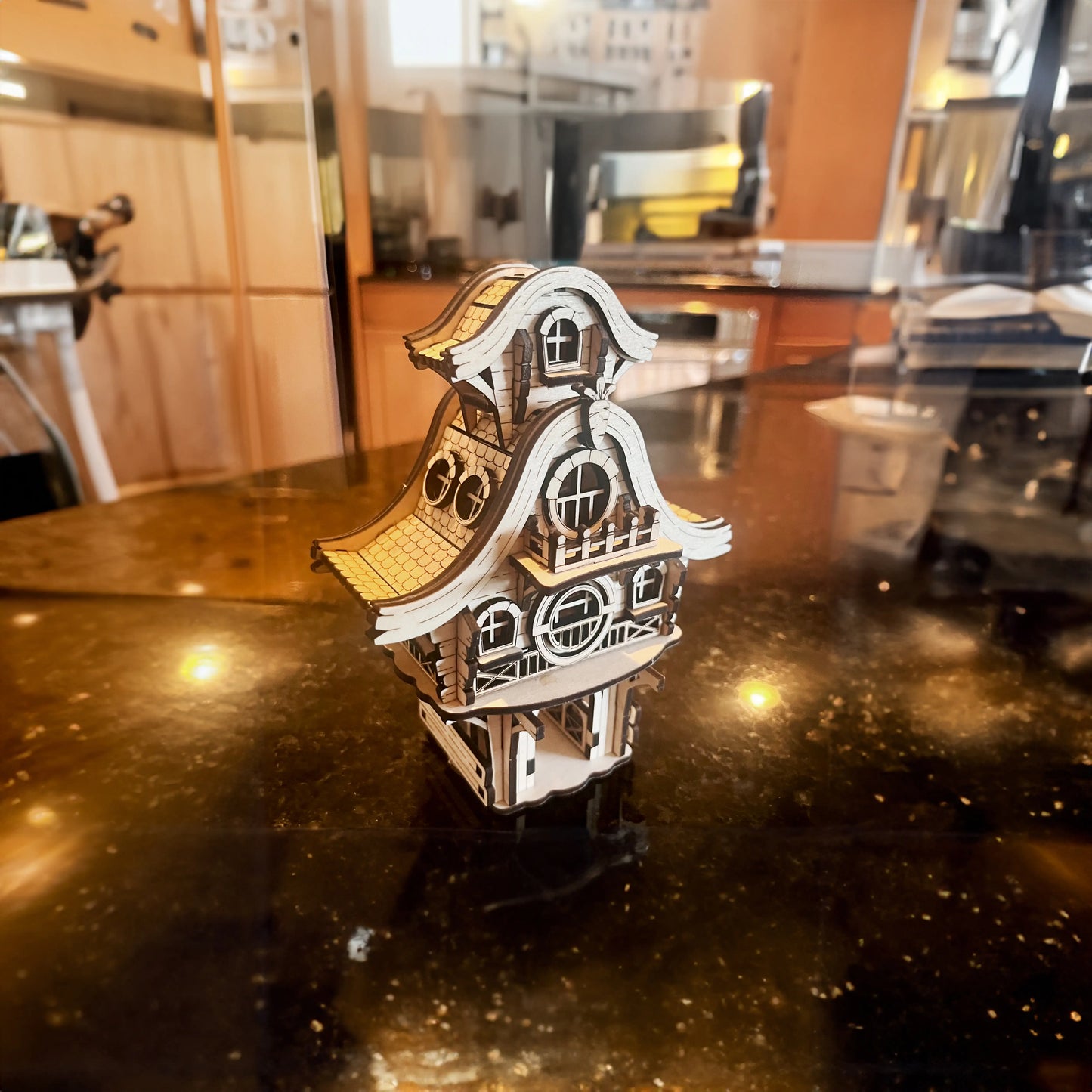 Side view of an assembled laser cut plywood easter bunny cottage miniature casting a sharp shadow on a rough outdoor stone.