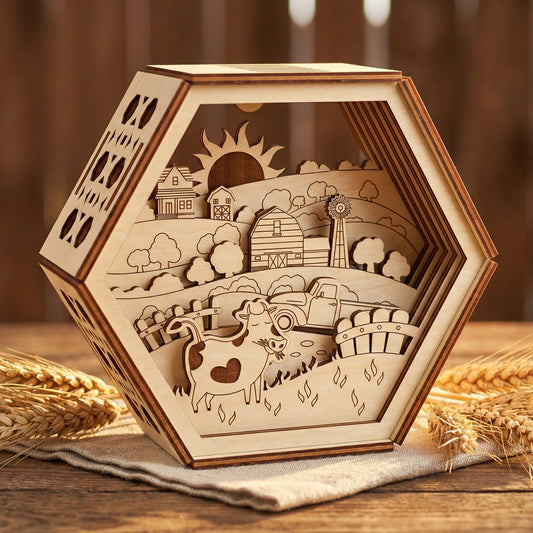 Hexagonal 3D farm scene made of layered laser cut plywood. Features a detailed cow with a heart spot, rustic barn, windmill, and sun. The natural wood grain and dark burnt edges create depth. Shown sitting on a linen cloth next to wheat stalks.
