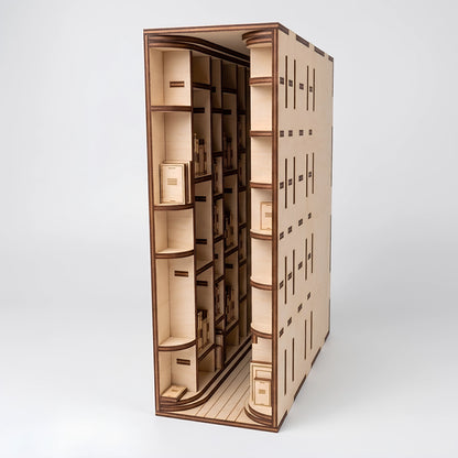 Studio view of an open laser-cut birch plywood library book nook model, showing miniature bookshelves and dark laser edges.